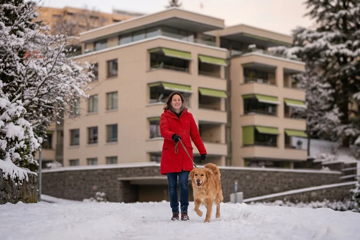 A woman walking her dog along the snowy path by the entrance